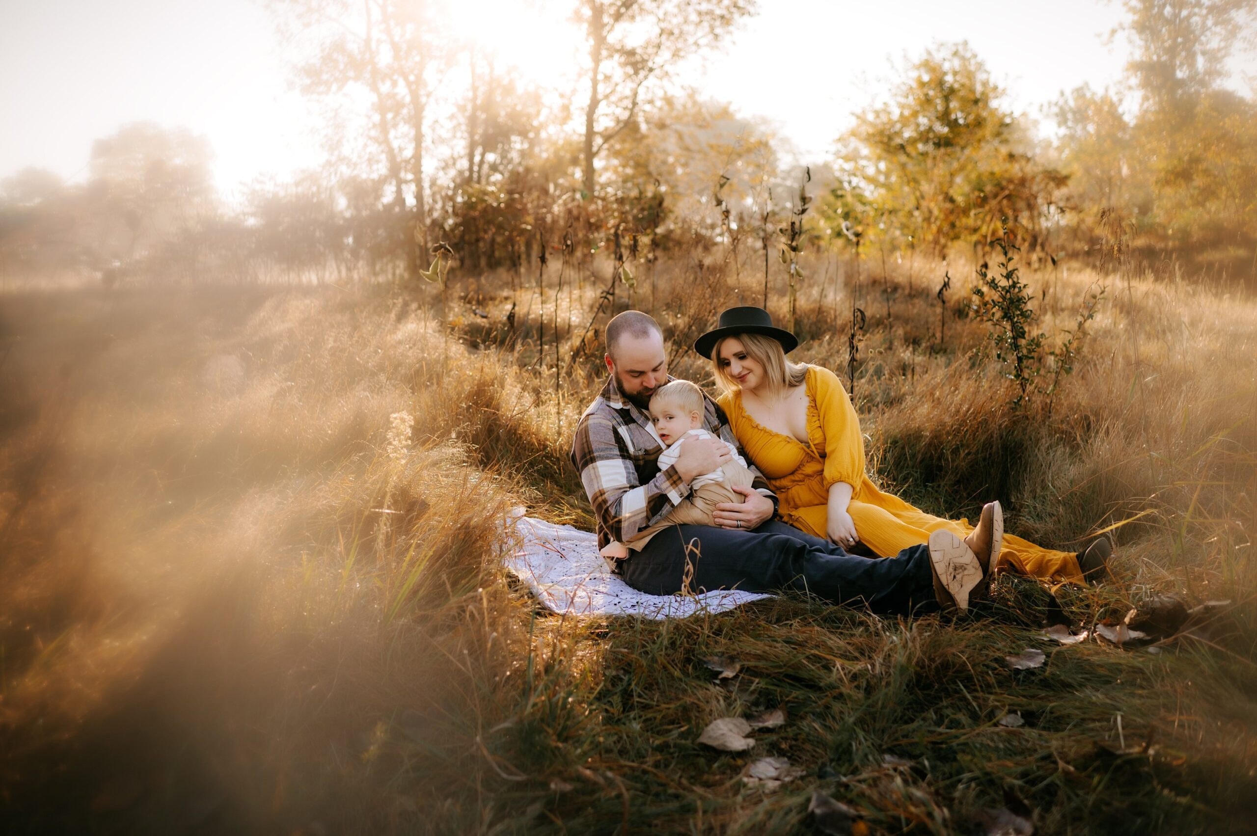 Findlay Ohio Photographer family of 3 hugging sitting in grassy field photo by cynthia dawson photography