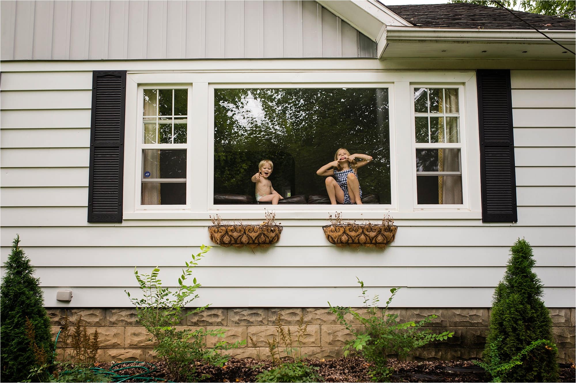 7 Ways to Use the Environment Around You to Frame Your Subject two kids looking out the window photo by Cynthia Dawson Photography 