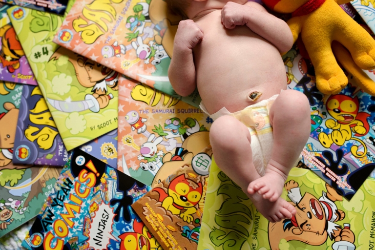 Northwest Ohio Newborn Lifestyle Photographer baby laying on comic books photo by Cynthia Dawson Photography