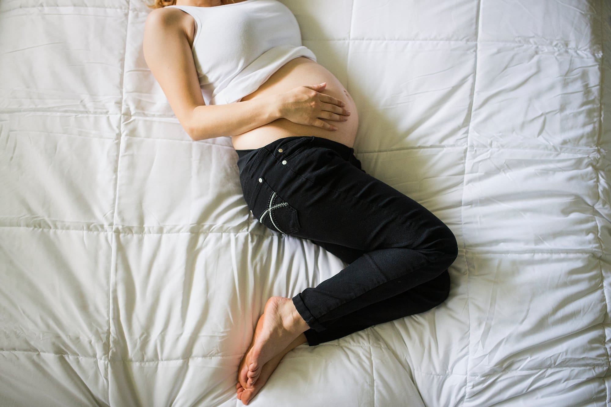 Lifestyle Maternity Photographer pregnant woman on bed from above photo by Cynthia Dawson Photography