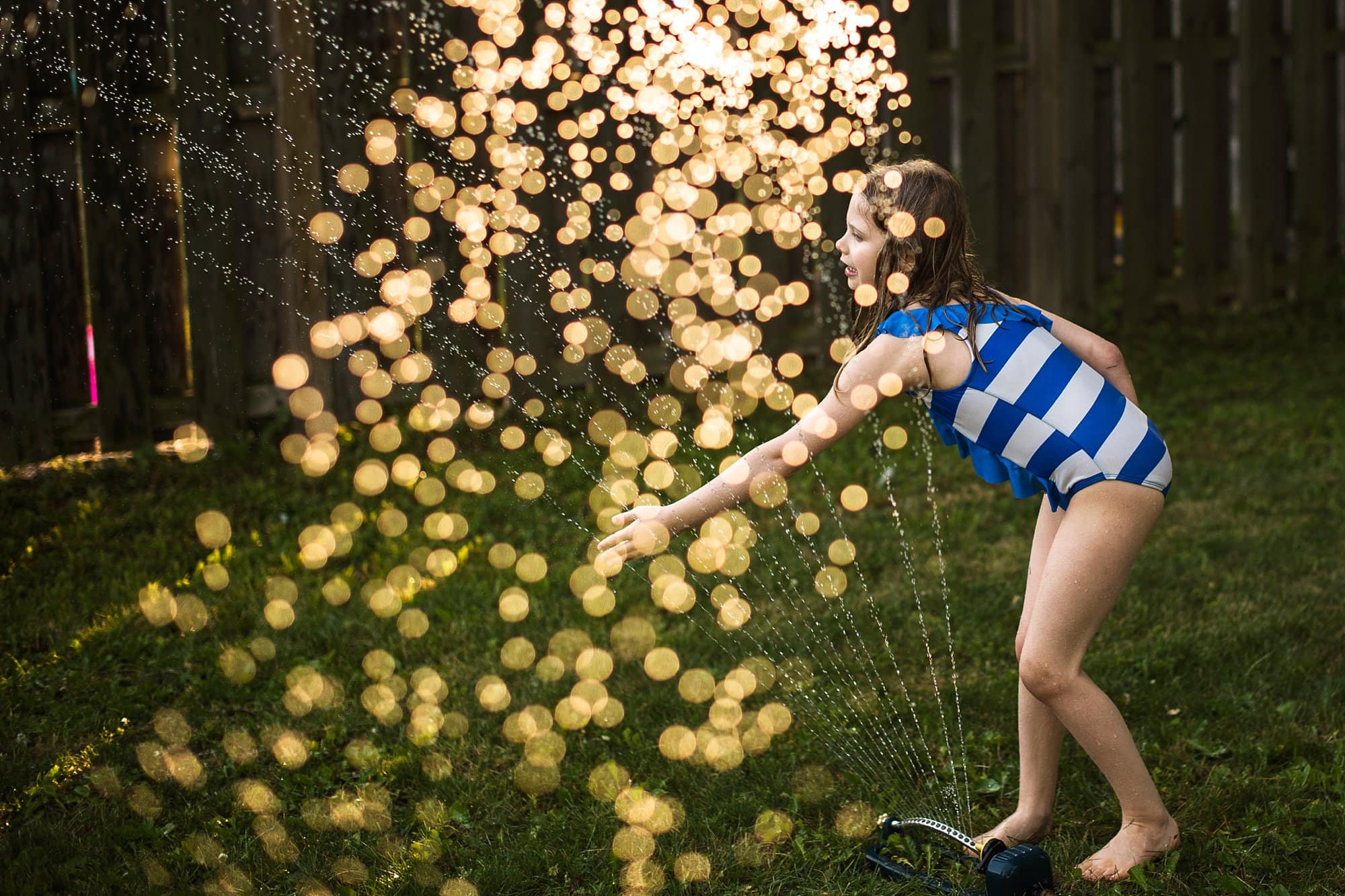 Toledo Ohio Summer Photo Session girl playing in sprinkler photo by Cynthia Dawson Photography