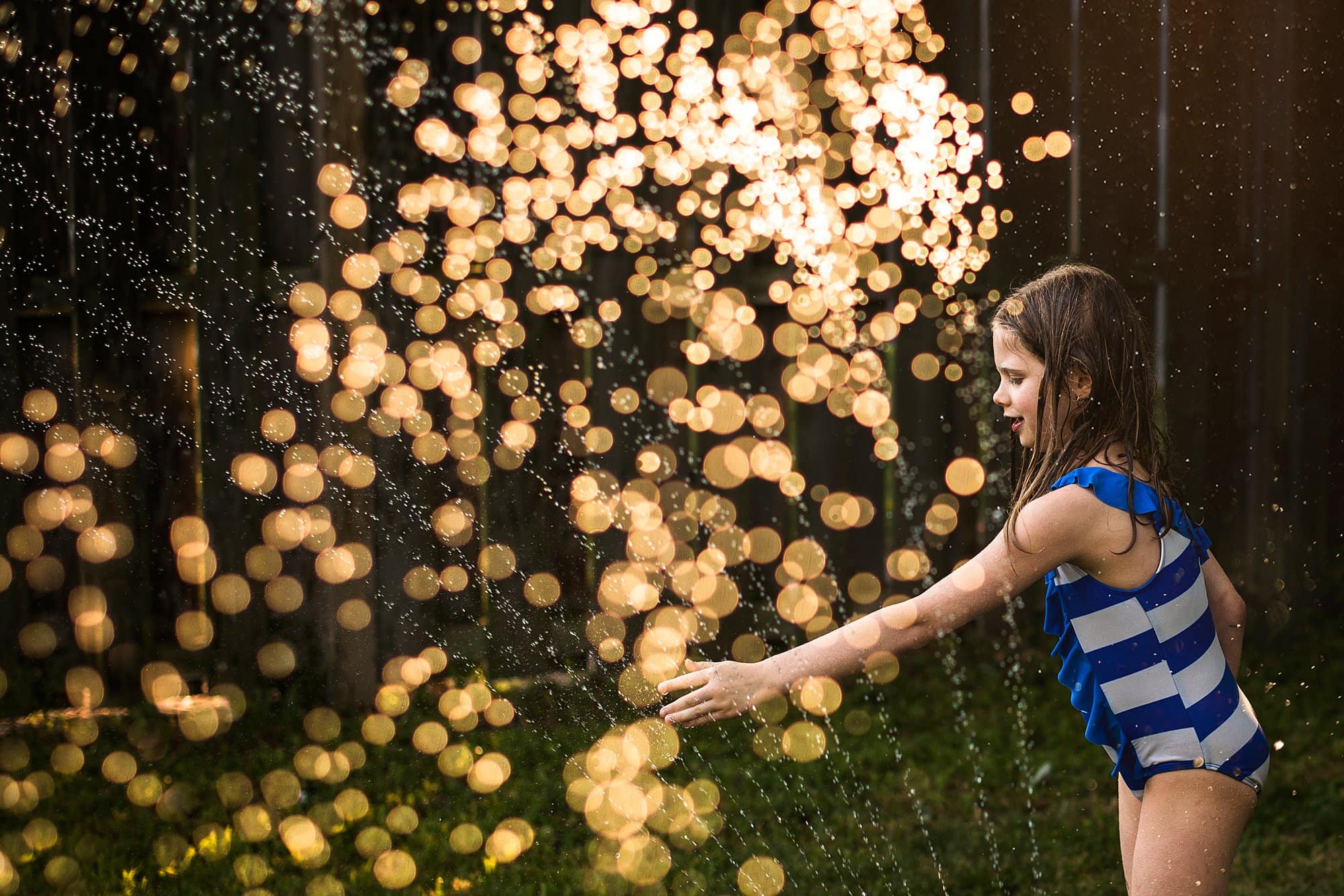 Family Photographer Northwest Ohio girl in sprinkler photo by Cynthia Dawson Photography