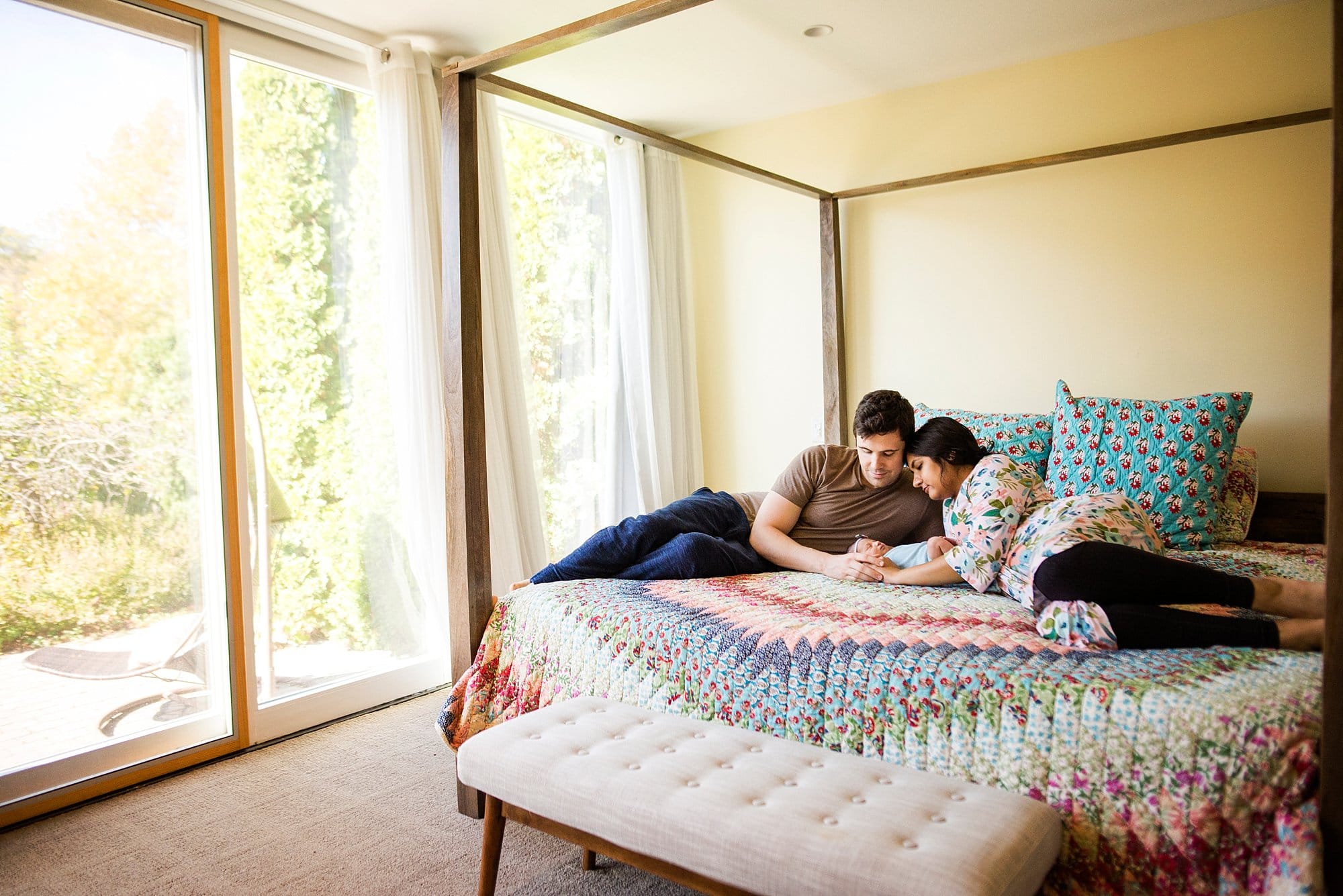 Toledo Ohio Newborn Lifestyle Photography parents on bed looking at newborn photo by Cynthia Dawson Photography