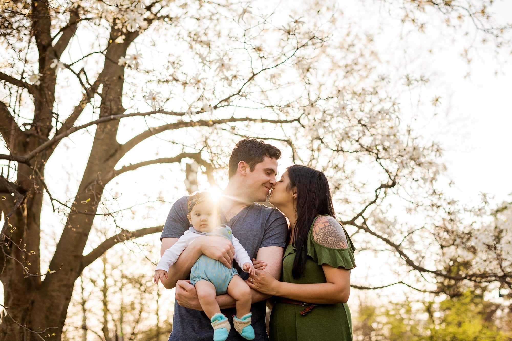 Toledo Lifestyle Family Photographer mom and dad kissing while holding baby photo by cynthia dawson photography